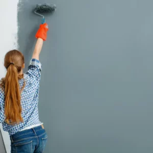 femme peintre en bâtiment appliquant de la peinture sur un mur intérieur