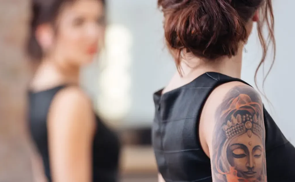 Femme tatouée face à un miroir, symbole de la culture du tatouage et réseaux sociaux en 2025